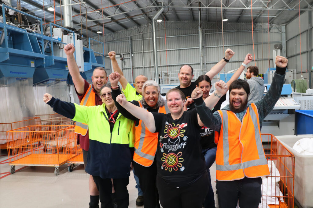 Image of Flagstaff laundry staff with arms up cheering